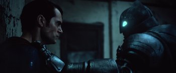 Movie still from “Batman v Superman: Dawn of Justice” (2016), directed by Zack Snyder – A man and a robot face each other in a dark room; Close Up shot, Over the shoulder angle