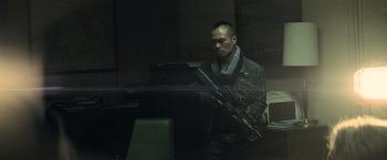 Movie still from “Batman v Superman: Dawn of Justice” (2016), directed by Zack Snyder – A man holding a rifle in a room; Medium shot, Over the shoulder angle