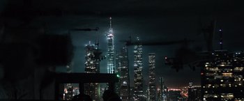 Movie still from “Batman v Superman: Dawn of Justice” (2016), directed by Zack Snyder – A helicopter flying in front of tall buildings at night; Extreme Wide shot, Low angle
