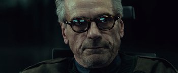 Movie still from “Batman v Superman: Dawn of Justice” (2016), directed by Zack Snyder – An older man wearing glasses looking at the camera; Close Up shot, Low angle