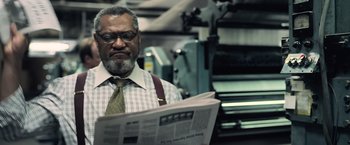 Movie still from “Batman v Superman: Dawn of Justice” (2016), directed by Zack Snyder – A man reading a newspaper while wearing a tie; Close Up shot, Low angle