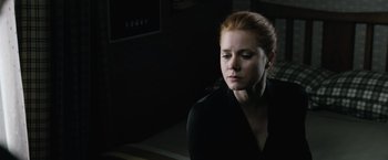 Movie still from “Batman v Superman: Dawn of Justice” (2016), directed by Zack Snyder – A woman in a black shirt is looking down; Close Up shot, Over the shoulder angle