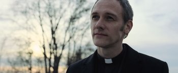 Movie still from “Batman v Superman: Dawn of Justice” (2016), directed by Zack Snyder – A man wearing a priest's outfit looking into the distance; Close Up shot, Low angle