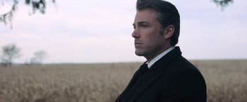 Movie still from “Batman v Superman: Dawn of Justice” (2016), directed by Zack Snyder – A man in a suit standing in a field; Close Up shot, Low angle