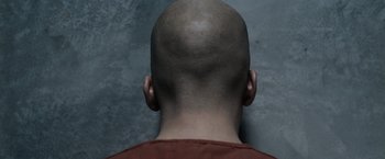 Movie still from “Batman v Superman: Dawn of Justice” (2016), directed by Zack Snyder – A man with a shaved head is seen from the neck down; Extreme Close Up shot, Overhead angle