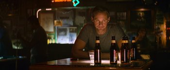 Movie still from “Battleship” (2012), directed by Peter Berg – A man sitting at a table with two beer bottles; Medium shot, Low angle