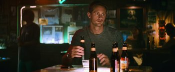 Movie still from “Battleship” (2012), directed by Peter Berg – A man sitting at a table in front of three bottles of beer; Medium shot, Over the shoulder angle