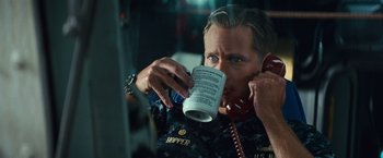 Movie still from “Battleship” (2012), directed by Peter Berg – A man holding a phone to his ear while holding a cup; Close Up shot, High angle