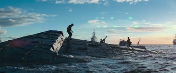 Movie still from “Battleship” (2012), directed by Peter Berg – A man riding a surfboard on top of a boat in the ocean; Extreme Wide shot, Low angle