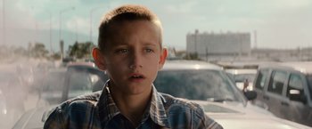 Movie still from “Battleship” (2012), directed by Peter Berg – A young boy in a plaid shirt looking at the camera; Close Up shot, Low angle
