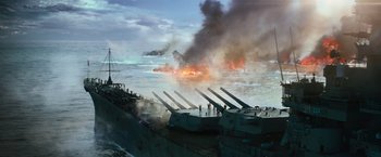 Movie still from “Battleship” (2012), directed by Peter Berg – A group of ships in the ocean with a fire in the background; Extreme Wide shot, High angle