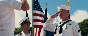 Movie still from “Battleship” (2012), directed by Peter Berg – A sailor saluting in front of an american flag; Medium shot, Low angle