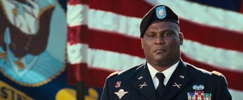 Movie still from “Battleship” (2012), directed by Peter Berg – A man in a military uniform standing in front of an american flag; Close Up shot, Low angle