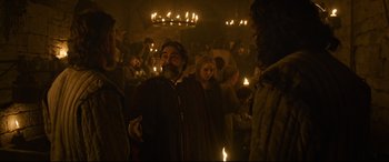 Movie still from “The Last Duel” (2021), directed by Ridley Scott – A group of people standing in a room holding candles; Medium shot, Over the shoulder angle