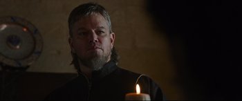 Movie still from “The Last Duel” (2021), directed by Ridley Scott – A man with long hair and beard standing next to a lit candle; Close Up shot, Over the shoulder angle