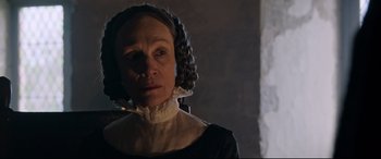 Movie still from “The Last Duel” (2021), directed by Ridley Scott – An older woman wearing a black dress and a wig; Close Up shot, Over the shoulder angle