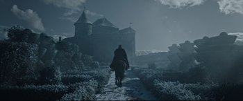 Movie still from “The Last Duel” (2021), directed by Ridley Scott – A man riding on the back of a horse down a snowy path; Extreme Wide shot, Low angle