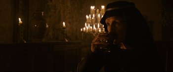 Movie still from “The Last Duel” (2021), directed by Ridley Scott – A man drinking a glass of wine in front of candles; Close Up shot, Over the shoulder angle
