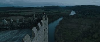 Movie still from “The Last Duel” (2021), directed by Ridley Scott – A man standing on top of a stone wall near a river; Extreme Wide shot, High angle