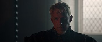 Movie still from “The Last Duel” (2021), directed by Ridley Scott – A person wearing a suit and tie; Close Up shot, Over the shoulder angle