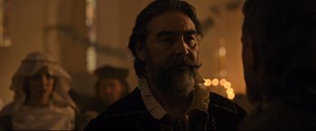 Movie still from “The Last Duel” (2021), directed by Ridley Scott – A man with long hair and a beard smoking a cigarette; Close Up shot, Over the shoulder angle