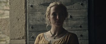 Movie still from “The Last Duel” (2021), directed by Ridley Scott – A woman wearing a yellow dress and a necklace; Close Up shot, Low angle