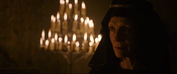 Movie still from “The Last Duel” (2021), directed by Ridley Scott – An old woman wearing a black hat and a black robe; Close Up shot, Low angle