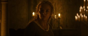 Movie still from “The Last Duel” (2021), directed by Ridley Scott – A woman with blonde curly hair wearing a necklace; Close Up shot, Low angle