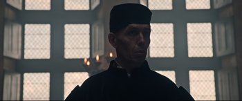 Movie still from “The Last Duel” (2021), directed by Ridley Scott – A man wearing a black hat in front of a window; Close Up shot, Low angle