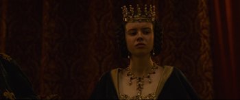 Movie still from “The Last Duel” (2021), directed by Ridley Scott – A woman wearing a gold crown and a black dress; Close Up shot, Low angle
