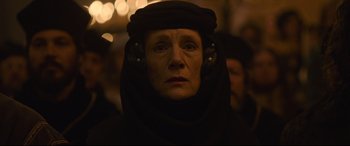 Movie still from “The Last Duel” (2021), directed by Ridley Scott – An older woman wearing a black headpiece and headphones; Close Up shot, Low angle
