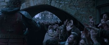 Movie still from “The Last Duel” (2021), directed by Ridley Scott – A group of people standing in front of an arch; Medium shot, Low angle