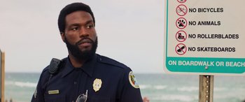 Movie still from “Baywatch” (2017), directed by Seth Gordon – A man in a police uniform standing next to the ocean; Close Up shot, Over the shoulder angle