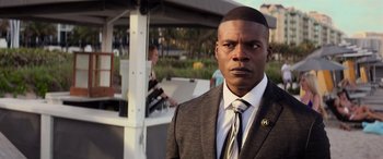 Movie still from “Baywatch” (2017), directed by Seth Gordon – A man in a suit and tie standing outside; Close Up shot, Over the shoulder angle