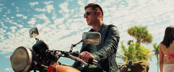 Movie still from “Baywatch” (2017), directed by Seth Gordon – A man riding a motorcycle on a sunny day; Medium shot, Low angle