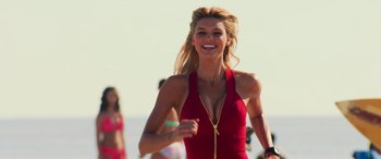 Movie still from “Baywatch” (2017), directed by Seth Gordon – A woman in a red dress running on the beach; Medium shot, Over the shoulder angle