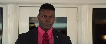 Movie still from “Baywatch” (2017), directed by Seth Gordon – A man wearing a suit and tie with a pink shirt; Close Up shot, Low angle