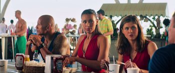 Movie still from “Baywatch” (2017), directed by Seth Gordon – A beautiful young lady sitting at a table with other people; Close Up shot, Over the shoulder angle