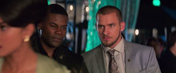 Movie still from “Baywatch” (2017), directed by Seth Gordon – Two men standing next to each other in front of green lights; Close Up shot, Over the shoulder angle