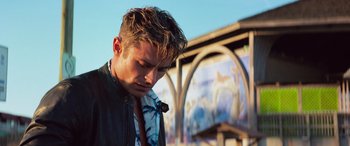 Movie still from “Baywatch” (2017), directed by Seth Gordon – A young man with a tie in front of a building; Close Up shot, Low angle