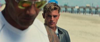 Movie still from “Baywatch” (2017), directed by Seth Gordon – A man standing next to another man on the beach; Close Up shot, Over the shoulder angle