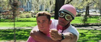 Movie still from “Baywatch” (2017), directed by Seth Gordon – A man and a man in a pink shirt and a pink helmet; Close Up shot, Over the shoulder angle