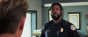 Movie still from “Baywatch” (2017), directed by Seth Gordon – A police officer looking into a mirror in a room; Close Up shot, Over the shoulder angle