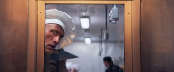 Movie still from “Baywatch” (2017), directed by Seth Gordon – A man wearing a chef's hat in a kitchen; Close Up shot, Over the shoulder angle