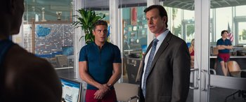 Movie still from “Baywatch” (2017), directed by Seth Gordon – Two men standing next to each other in an office; Medium shot, Over the shoulder angle