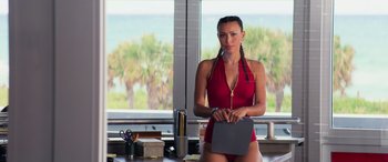 Movie still from “Baywatch” (2017), directed by Seth Gordon – A woman in a red bathing suit sitting in front of a window; Medium shot, Over the shoulder angle