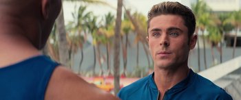 Movie still from “Baywatch” (2017), directed by Seth Gordon – A person with a palm tree in the background; Close Up shot, Over the shoulder angle