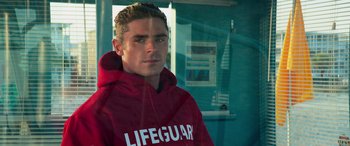 Movie still from “Baywatch” (2017), directed by Seth Gordon – A lifeguard is standing in front of a window; Close Up shot, Over the shoulder angle