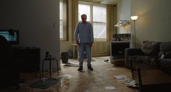 Movie still from “Beau Is Afraid” (2023), directed by Ari Aster – An older man standing in a messy living room; Wide shot, Low angle