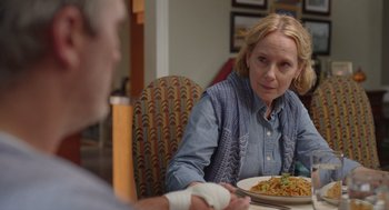 Movie still from “Beau Is Afraid” (2023), directed by Ari Aster – A woman sitting at a table with a plate of food; Close Up shot, Over the shoulder angle